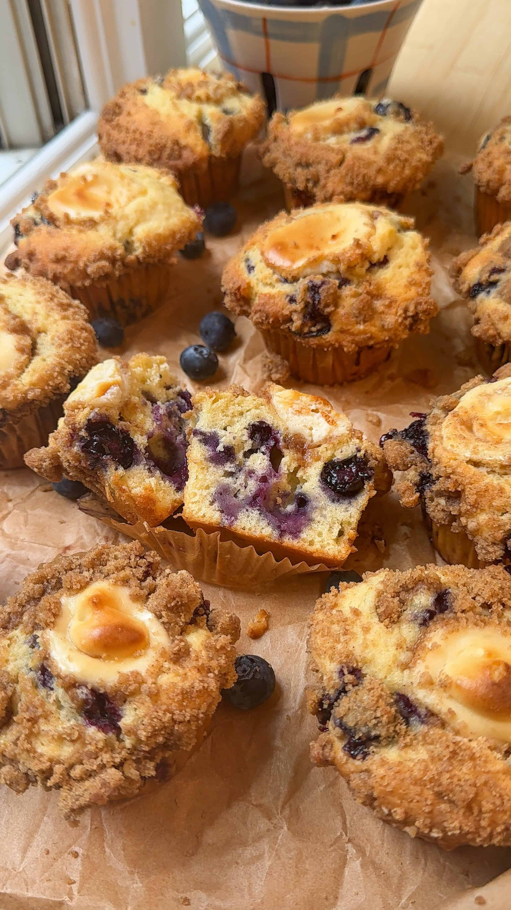 my cheesecake stuffed blueberry crumble muffins sliced in half on parchment paper ready to be enjoyed