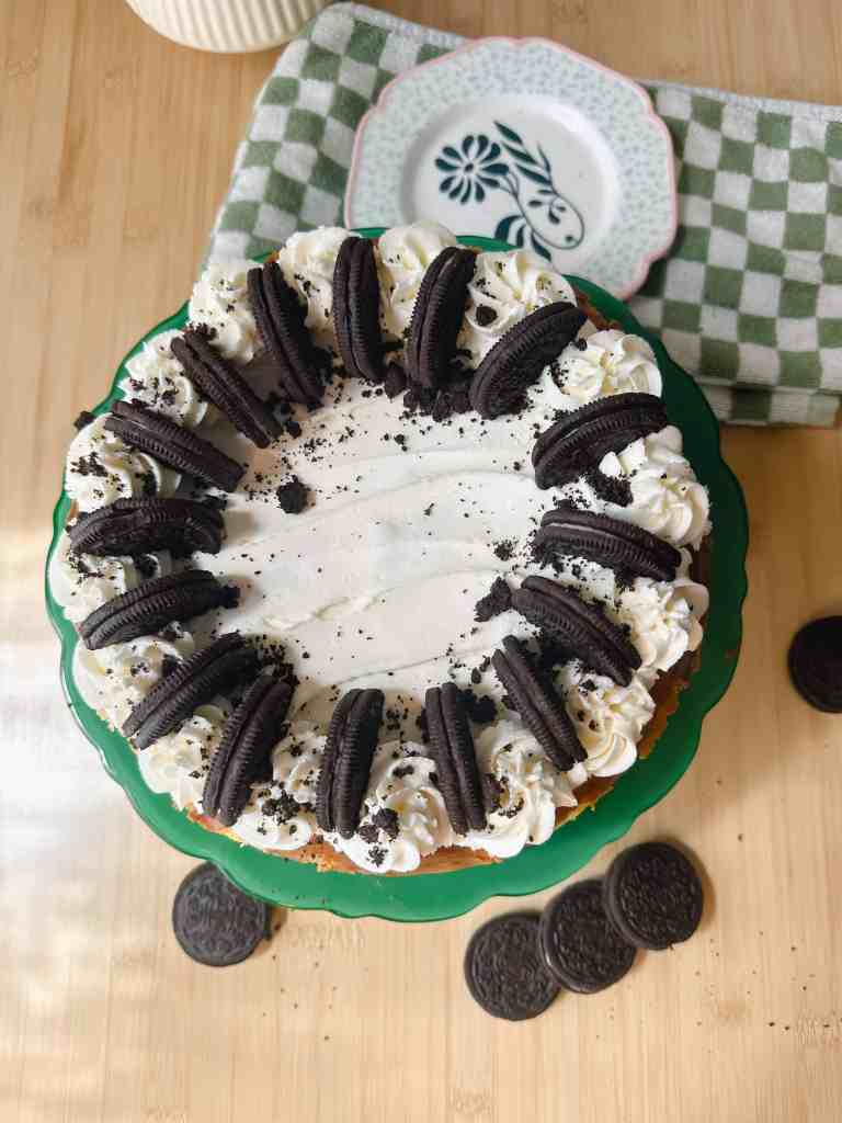 Top view of an entire Oreo cheesecake with a dark Oreo crust and scattered cookie crumbs on top.