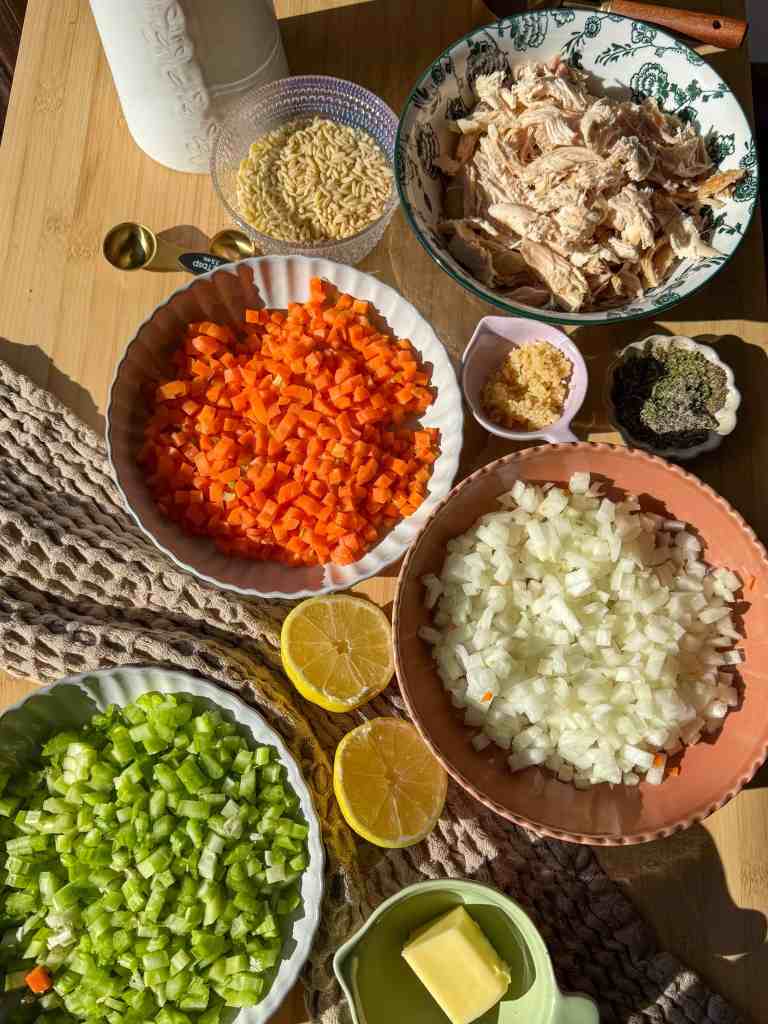 Ingredients for lemon chicken orzo soup including rotisserie chicken, orzo, bone broth, carrots, celery, onion, garlic, and lemon