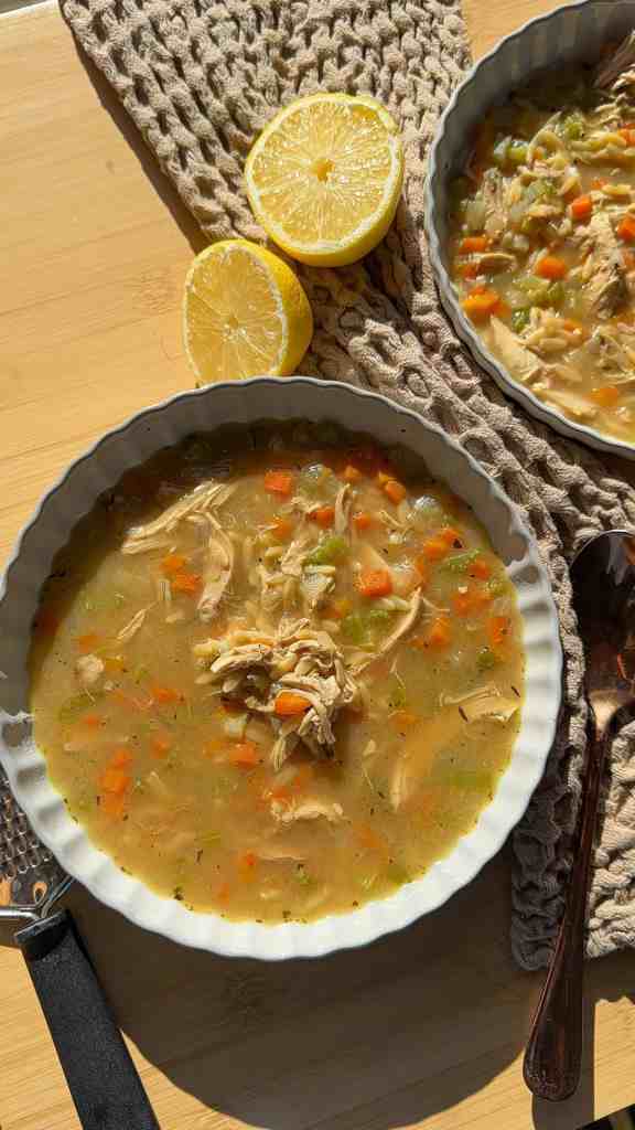 High protein chicken orzo soup in a white bowl topped with grated Parmesan