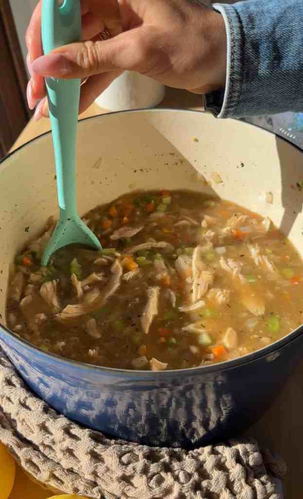 : Spoonful of lemon chicken orzo soup with tender orzo and shredded chicken