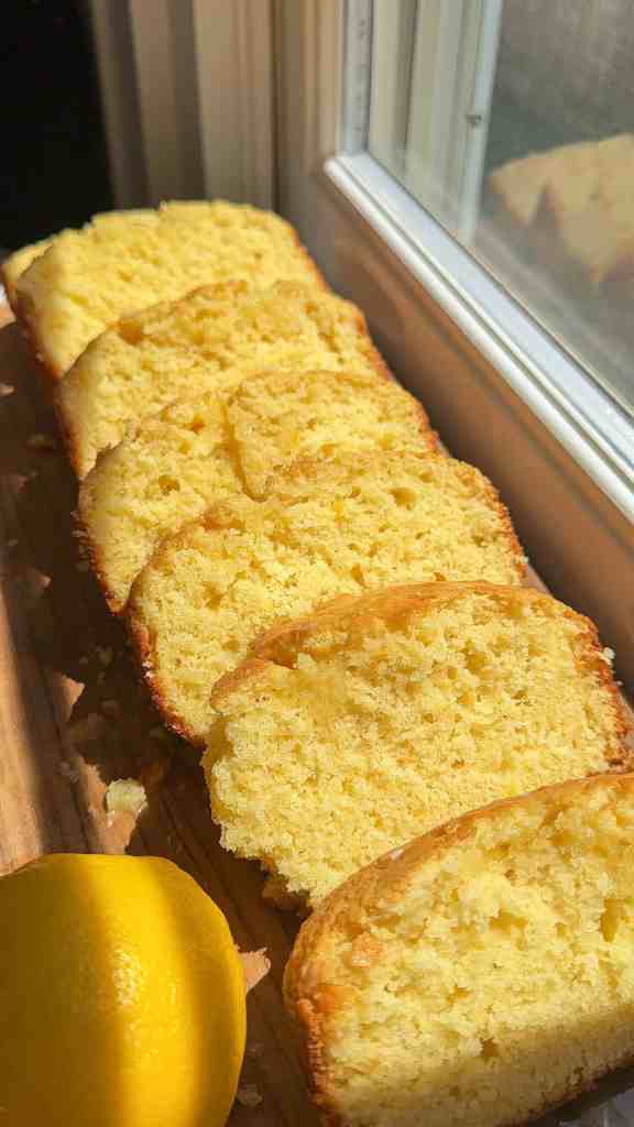 my iced lemon loaf sliced on a wooden cutting board