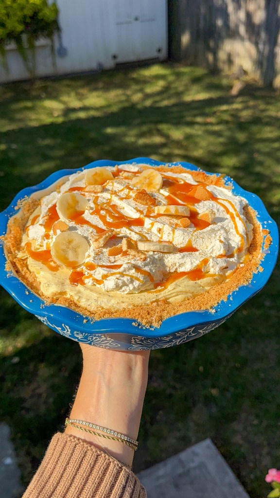 Banana pudding pie with whipped cream and salted caramel drizzle photographed outdoors in natural fall light