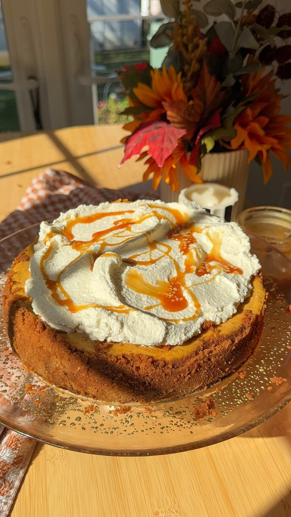 Pumpkin cheesecake with a Biscoff cookie crust topped with homemade whipped cream and salted caramel drizzle